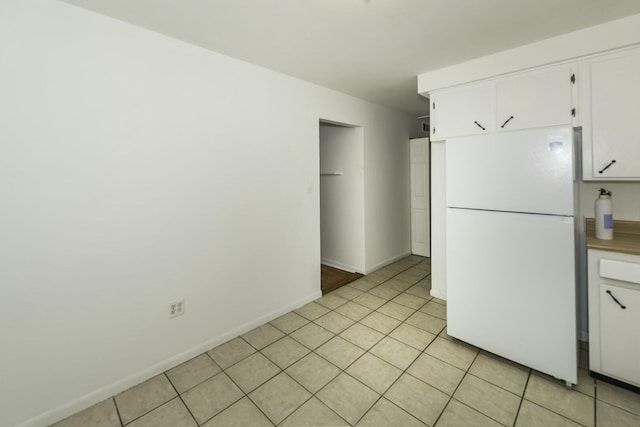 kitchen with white fridge, light tile patterned floors, and white cabinetry