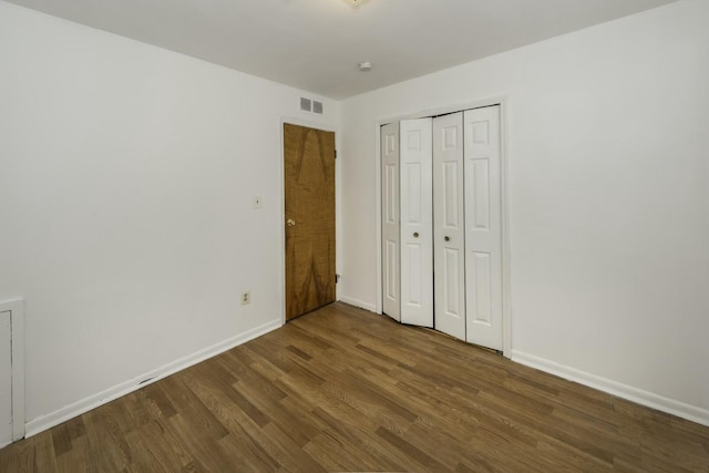 unfurnished bedroom with a closet and dark hardwood / wood-style floors