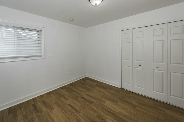 unfurnished bedroom with dark hardwood / wood-style flooring and a closet