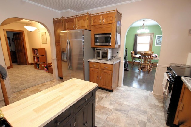 kitchen featuring light carpet, appliances with stainless steel finishes, wooden counters, ornamental molding, and decorative light fixtures