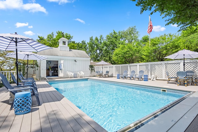 view of pool featuring a wooden deck and an outbuilding