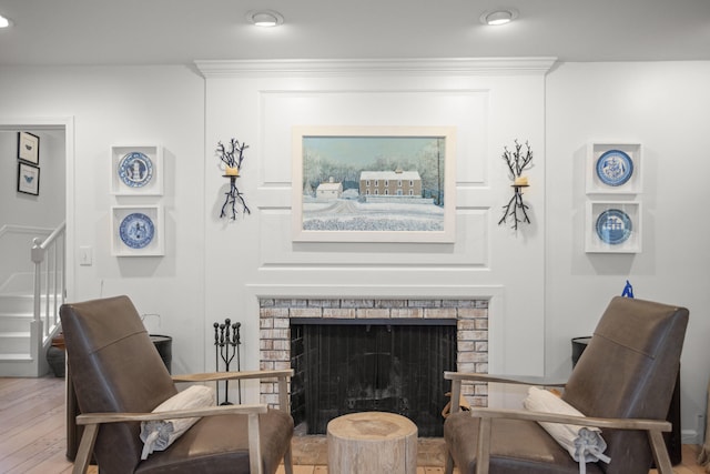 sitting room featuring hardwood / wood-style floors, a brick fireplace, and ornamental molding