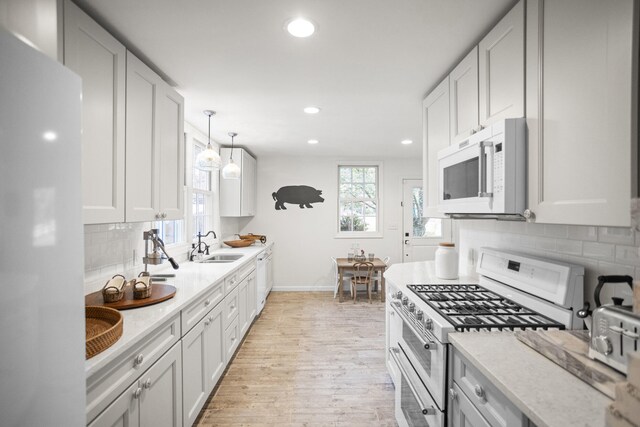 kitchen featuring light stone countertops, sink, white appliances, decorative backsplash, and white cabinets