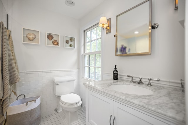 bathroom featuring tile patterned floors, vanity, toilet, and tile walls