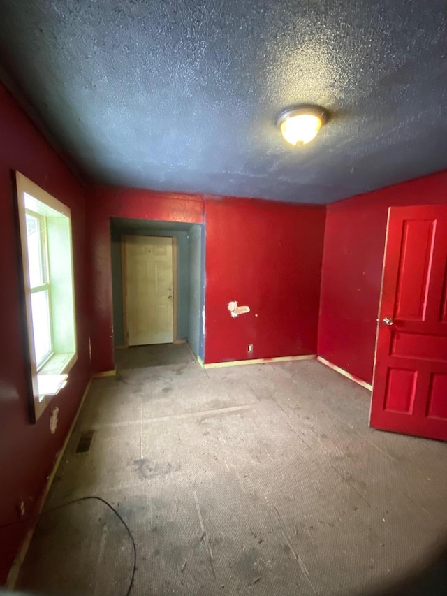 spare room featuring a textured ceiling, light colored carpet, and lofted ceiling