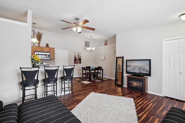 living room with ceiling fan with notable chandelier and dark hardwood / wood-style flooring