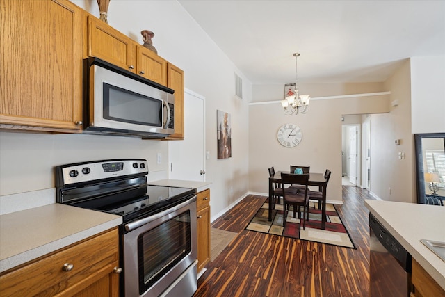 kitchen with lofted ceiling, dark hardwood / wood-style flooring, a chandelier, pendant lighting, and appliances with stainless steel finishes