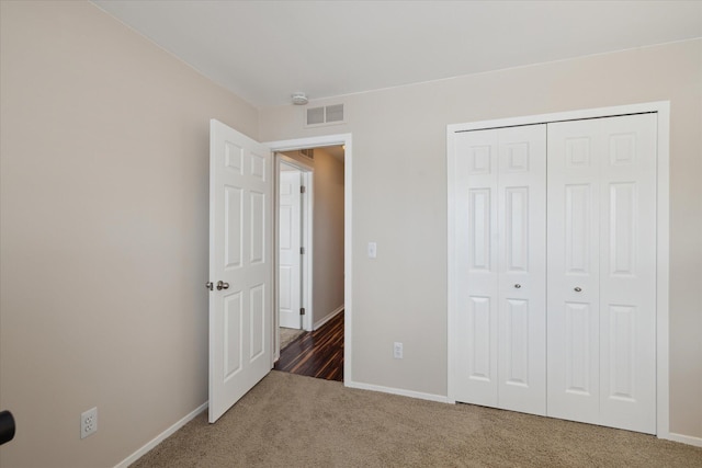 unfurnished bedroom featuring dark carpet and a closet