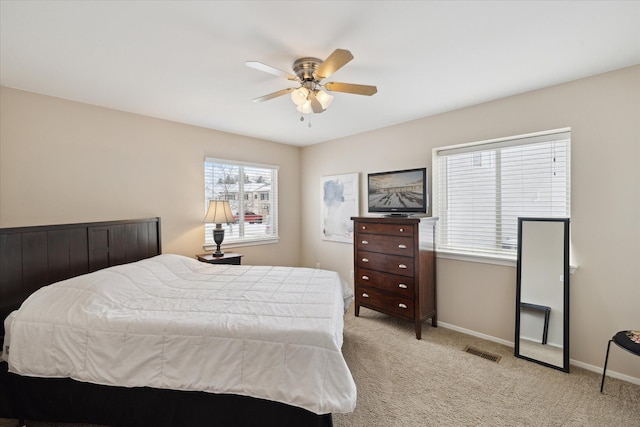 bedroom with multiple windows, light carpet, and ceiling fan