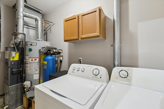 laundry room featuring water heater, independent washer and dryer, and cabinets