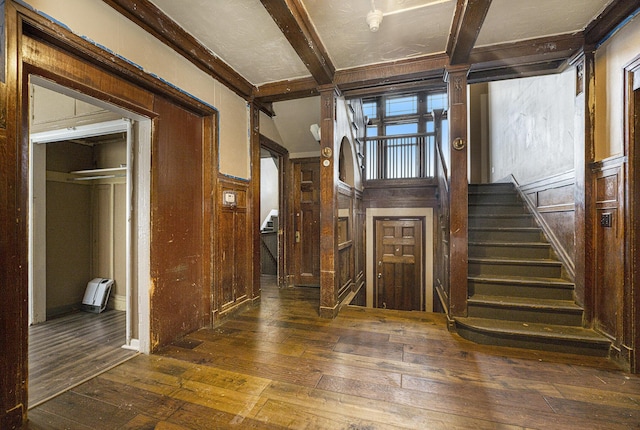 entryway featuring dark hardwood / wood-style flooring, wooden walls, and beamed ceiling