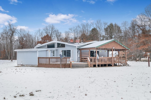 snow covered back of property featuring a wooden deck