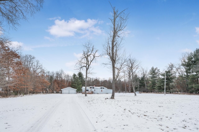 snowy yard with a garage and an outbuilding