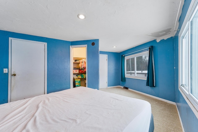 bedroom with a spacious closet, a closet, and light colored carpet