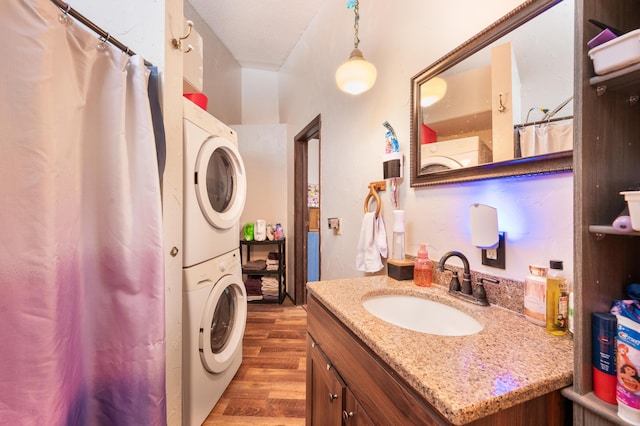 bathroom with vanity, stacked washer and clothes dryer, and hardwood / wood-style flooring