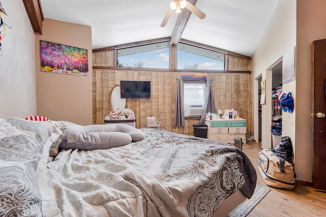 bedroom with vaulted ceiling with beams, ceiling fan, cooling unit, and light wood-type flooring