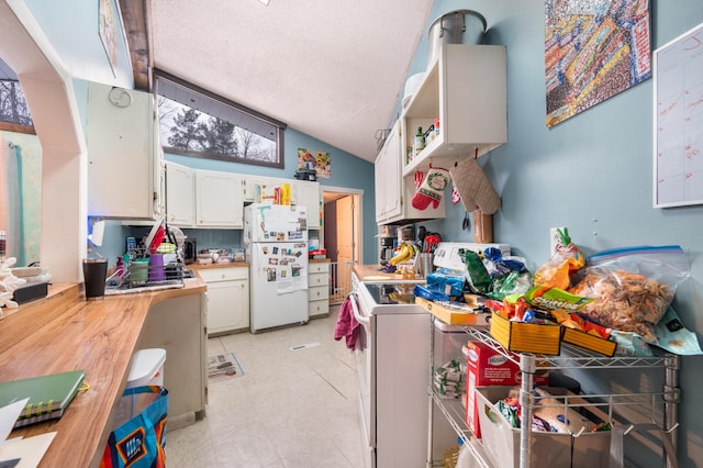 kitchen with white cabinets, white refrigerator, stove, and vaulted ceiling