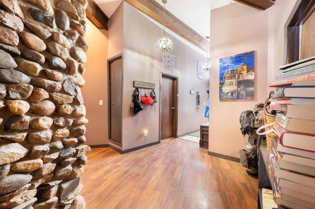 entryway featuring beamed ceiling, a notable chandelier, light wood-type flooring, and a towering ceiling
