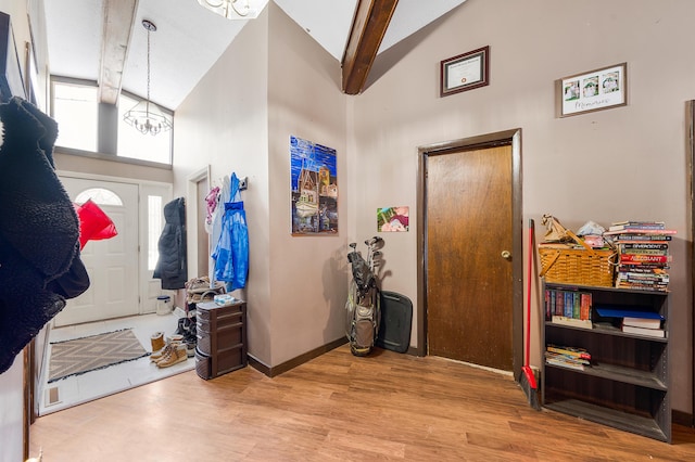 foyer with beam ceiling, light wood-type flooring, high vaulted ceiling, and a notable chandelier