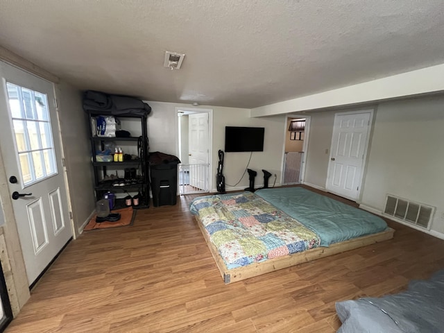 bedroom with a textured ceiling and light hardwood / wood-style floors