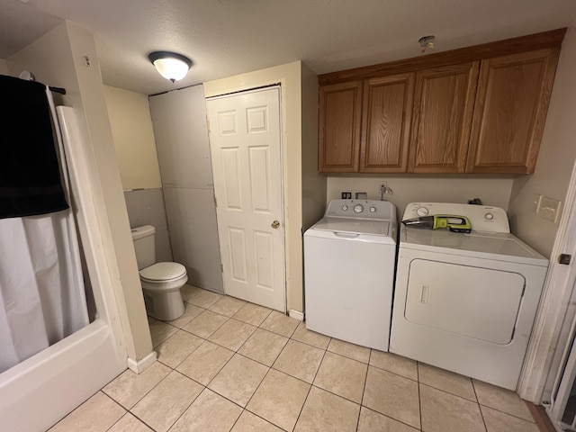 laundry room featuring cabinets, light tile patterned floors, a textured ceiling, and washing machine and clothes dryer