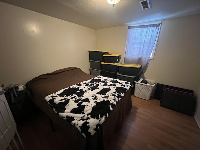 bedroom with dark hardwood / wood-style flooring and a textured ceiling