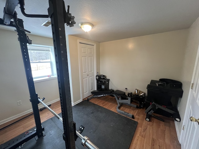 exercise room with wood-type flooring and a textured ceiling