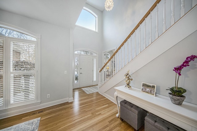 foyer entrance featuring a towering ceiling and light wood-type flooring