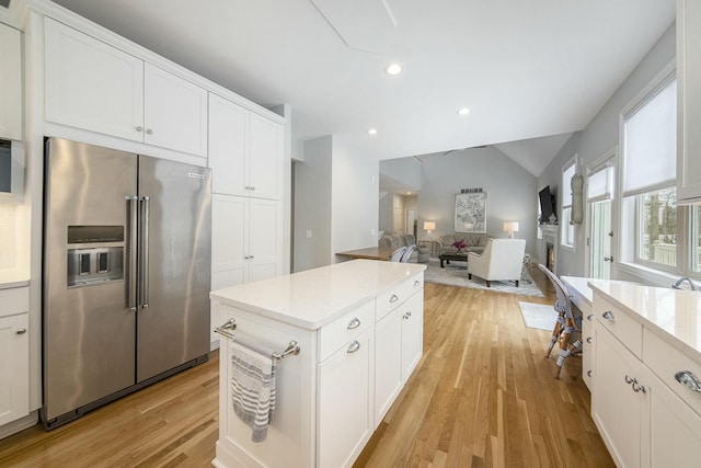 kitchen with high end fridge, white cabinets, and light hardwood / wood-style flooring