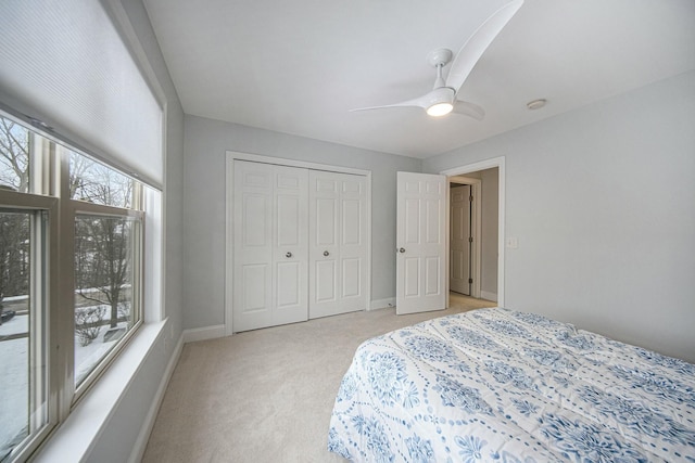 bedroom with a closet, ceiling fan, and light colored carpet