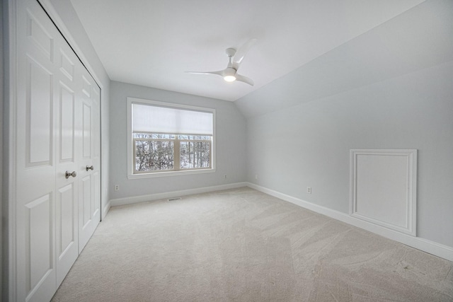 interior space featuring ceiling fan, light colored carpet, and vaulted ceiling