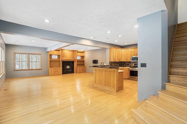 kitchen with stainless steel appliances, sink, light hardwood / wood-style floors, backsplash, and a kitchen island