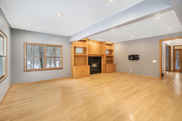 unfurnished living room featuring a textured ceiling and light hardwood / wood-style flooring