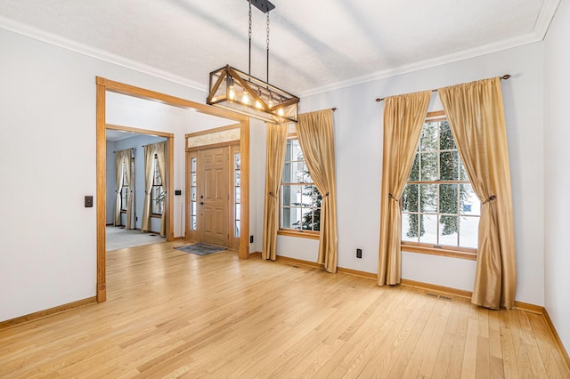 foyer entrance with ornamental molding and light hardwood / wood-style floors