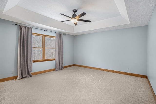 spare room featuring ceiling fan, light colored carpet, a raised ceiling, and a textured ceiling