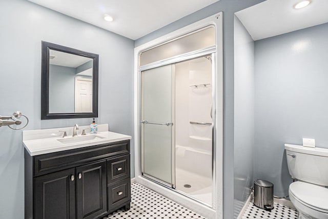 bathroom featuring toilet, vanity, and a shower with shower door