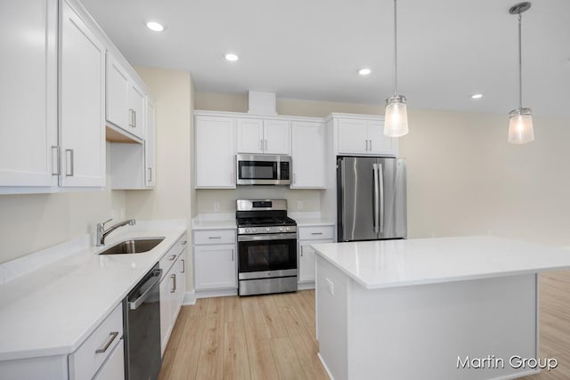 kitchen with decorative light fixtures, stainless steel appliances, white cabinetry, and sink