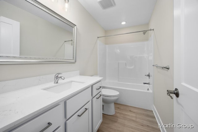 full bathroom with bathing tub / shower combination, hardwood / wood-style floors, vanity, and toilet