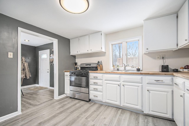 kitchen with white cabinets, light hardwood / wood-style floors, stainless steel range with gas cooktop, and sink