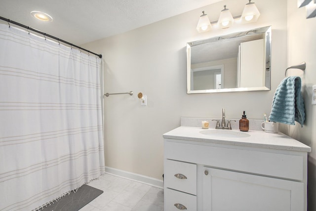 bathroom with tile patterned flooring, vanity, and a textured ceiling