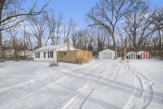 yard covered in snow featuring a garage and a storage shed