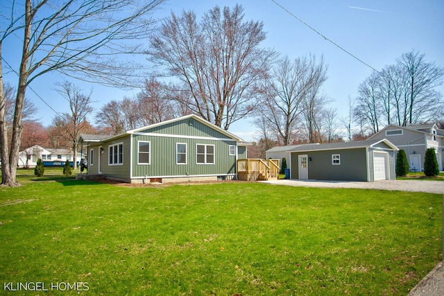 view of front of property featuring a detached garage, an outbuilding, gravel driveway, and a front lawn