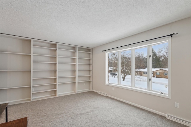 carpeted spare room with baseboard heating and a textured ceiling