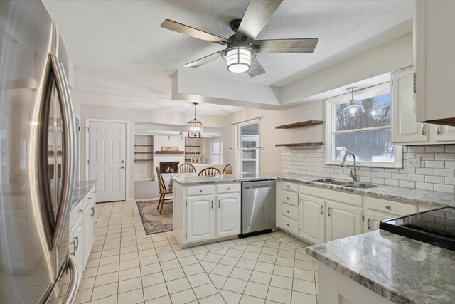 kitchen with sink, kitchen peninsula, appliances with stainless steel finishes, and white cabinetry