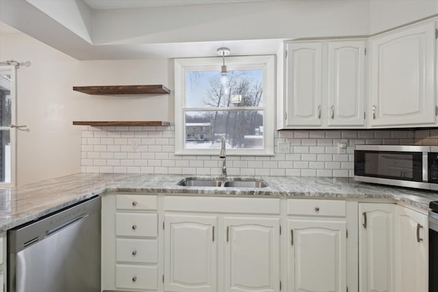 kitchen with appliances with stainless steel finishes, tasteful backsplash, white cabinets, pendant lighting, and sink