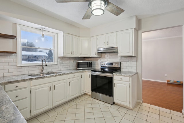 kitchen with appliances with stainless steel finishes, light tile patterned floors, sink, and white cabinetry