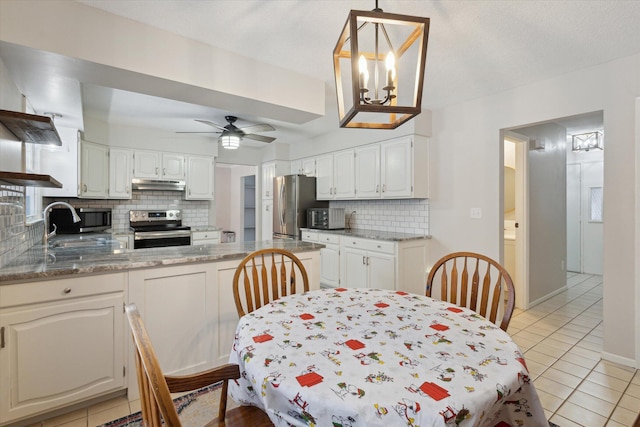 tiled dining room featuring ceiling fan with notable chandelier and sink