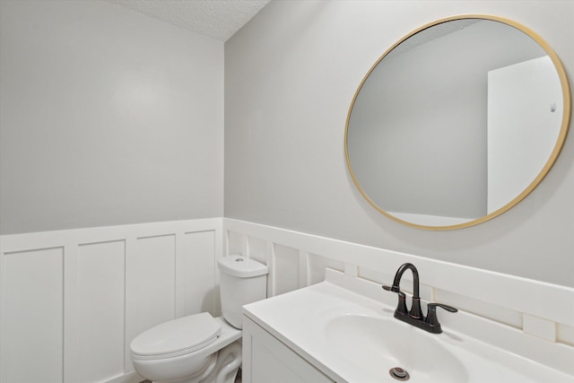 bathroom with a textured ceiling, toilet, and vanity