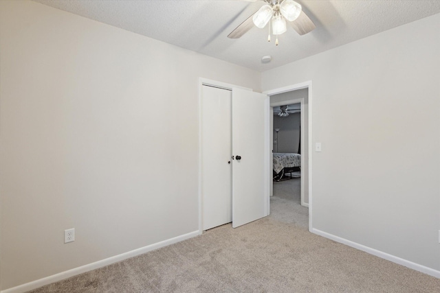 unfurnished bedroom featuring a textured ceiling, a closet, light colored carpet, and ceiling fan