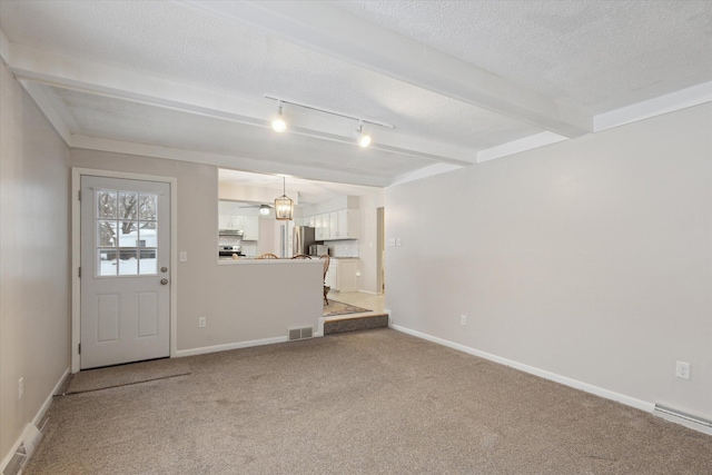 interior space featuring baseboard heating, track lighting, a textured ceiling, beamed ceiling, and carpet flooring